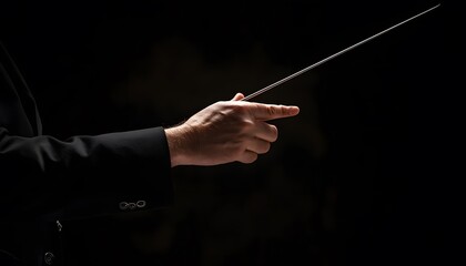 A conductors hand holding a baton against a black background