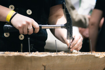 Zimmerin klopft Nägel in Holz