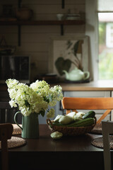 rustic cottage house kitchen with summer vegetable harvest on wooden table and bouquet of hydrangeas. Simple country living