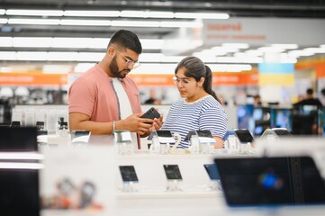 Tech shopping device gadget concept. Happy young people buying a new smartphone in mobile shop