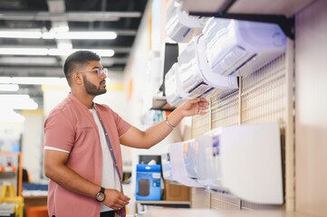 An Indian man is choosing a new air conditioner in an electronics store
