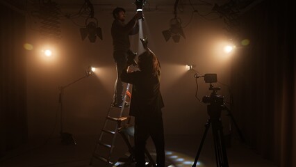 Studio for photo video production filming with lighting equipment and cyclorama, team members...