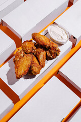 Crispy chicken wings served with white dipping sauce on vibrant orange background