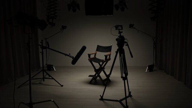 Studio for photo video production filming with lighting equipment, cyclorama and camera, director chair stand in the middle of dark scene.