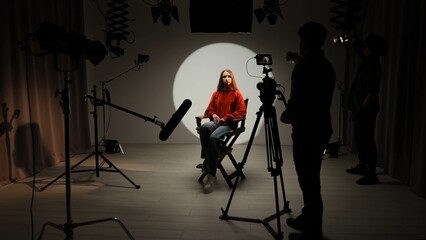 Studio for photo video production with lighting equipment and cyclorama, model actress sits on...