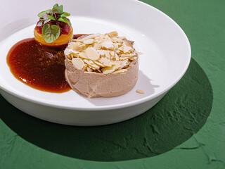 Dessert featuring almond mousse with fruit sauce and fresh garnish served on a white plate