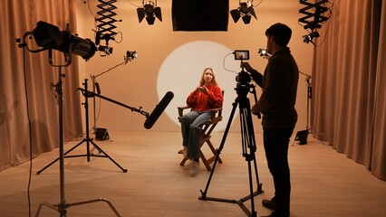 Studio for photo video production filming with lighting equipment and cyclorama, model actress sits...