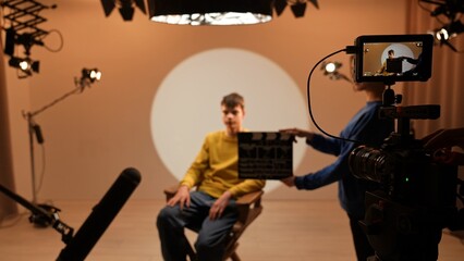 Studio for photo video production filming with lighting equipment and cyclorama, assistant holds...