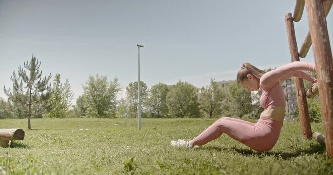 A young woman performs calisthenics exercises in a sunny park, showcasing fitness, health, and an active lifestyle.