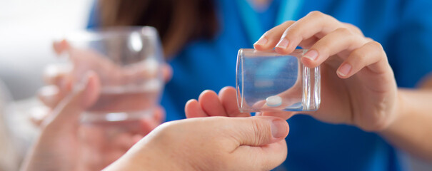 Closeup hand of nurse giving drugs patient elderly woman with dementia or alzheimer in living room...
