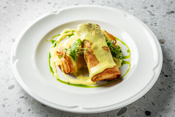 Delicious pancakes rolled and drizzled with creamy sauce, garnished with fresh greens. A visually appealing dish perfect for breakfast or brunch settings. Ideal for food-related projects.