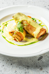Delicious pancakes rolled and drizzled with creamy sauce, garnished with fresh greens. A visually appealing dish perfect for breakfast or brunch settings. Ideal for food-related projects.