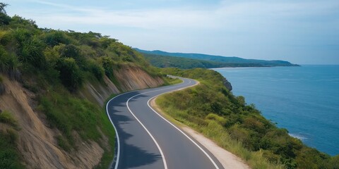 A winding road with a beautiful view of the ocean. The road is lined with trees and the water is calm
