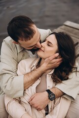 strong embrace of a man and a woman in love posing for a photo in front of a city lake in the cool season, having fun together, selective focus, noise effect