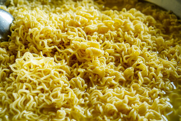 A detailed close up shot of a bowl filled with cooked instant noodles. The noodles are golden...