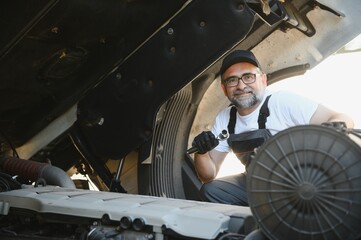 A senior worker checks wheel. Truck malfunction. Service work