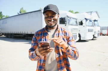 Professional truck driver holding smart phone in front of the trucks