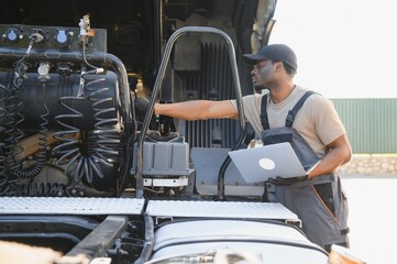 Truck repair service. African american Mechanic makes computer diagnostic of the semitruck