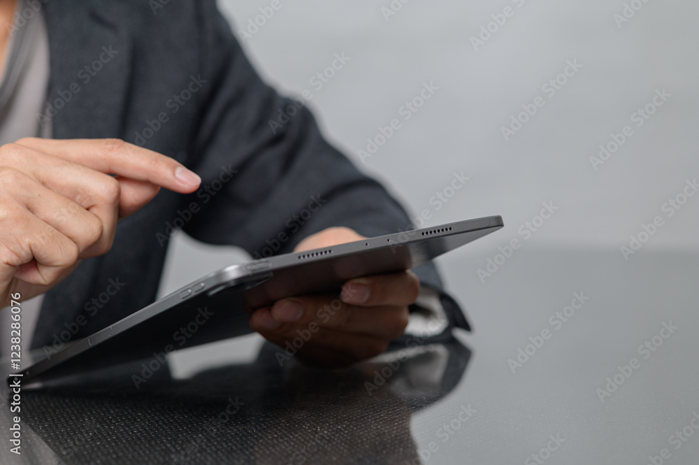 Poster person using tablet device with focused gesture in a modern setting