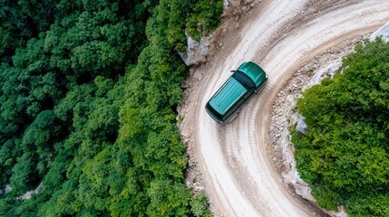 Aerial view of a green vehicle navigating a winding dirt road through lush forest.