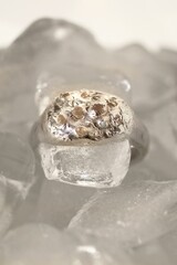 Stunning minimalist silver ring with unique design and gemstones on a clear ice cubes background