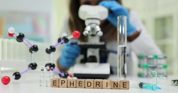 A scientist studies ephedrine under a microscope, examining its molecular structure with lab tools and equipment