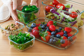 Healthy vegan food preparations for week in glass containers. Vegetables, nuts, berries in boxes.