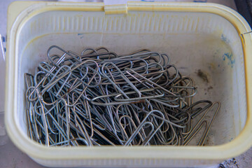 paper clips in a dirty box on a desk in an old abandoned manufacturing plant. pipe connections.