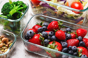 Healthy vegan food preparations for week in glass containers. Vegetables, nuts, berries in boxes.