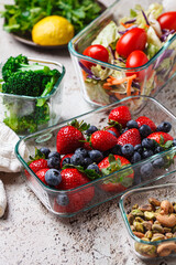 Healthy vegan food preparations for week in glass containers. Vegetables, nuts, berries in boxes.