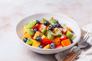 Fruit salad with kiwi, persimmon, berries and poppy seed dressing.