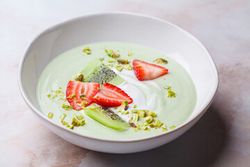 Green matcha yogurt with berries and pistachio. Vegan breakfast concept.