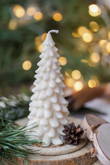 Beautiful soy wax candles in the room, decorated with fir tree branches, Christmas lights in the backgound