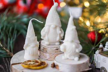 Beautiful soy wax candles in the room, decorated with fir tree branches, Christmas lights in the backgound