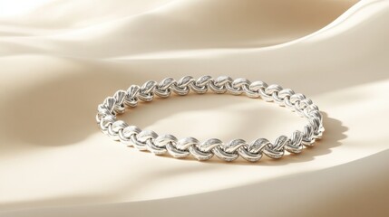 A designer silver bracelet placed on a luxury cream-colored background