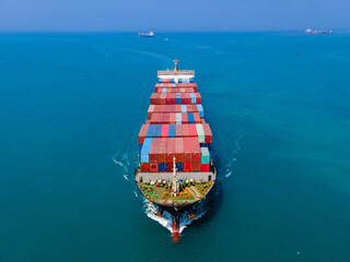 the aerial perspective of a cargo ship being loaded and unloaded at a bustling seaport and sailing...