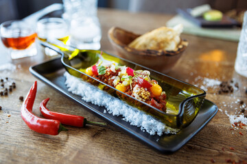 Beef tartare from Black Angus. Egg yolk, pickled cucumber, shallot, pearl onion, coriander and mustard seeds. Delicious healthy Italian food served for lunch in modern gourmet cuisine restaurant