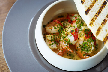 Shrimp pil-pil. King prawns, garlic, chilli and baguette. Delicious Spanish traditional food closeup served for lunch in modern gourmet cuisine restaurant