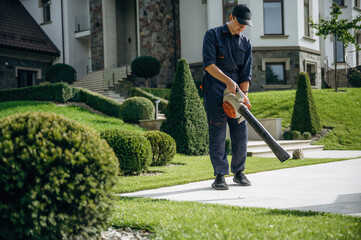 Using leaf blower. Professional gardener is on the lawn