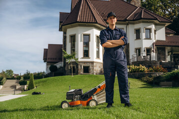 Standing with arms crossed. Professional gardener is on the lawn