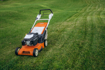 Obraz premium Lawn mover is on the green grass at daytime