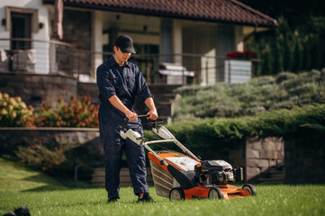 Fuel powered lawn mover, cutting the grass. Professional gardener is on the lawn