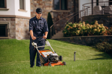 Fuel powered lawn mover, cutting the grass. Professional gardener is on the lawn