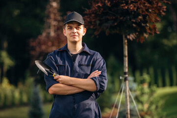 Standing with arms crossed. Professional gardener is on the lawn