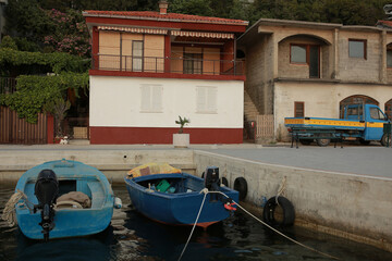 A picturesque harbor during sunset, with fishing boats docked by stone Medieval houses and fishing...