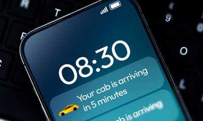 Cab arriving notification on smartphone screen close up with keyboard in the backdrop. Online cab booking concept background
