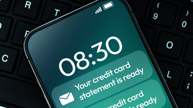 Credit card statement ready notification appearing on the smartphone with keyboard in the backdrop, banking and finance concept