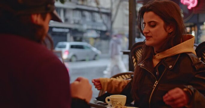 Two friends enjoy coffee and pastries at a Parisian cafe, discussing life and sharing a moment together on a rainy day.