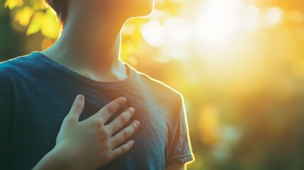 Golden Hour Hope: A young boy, bathed in the warm glow of the setting sun, places his hand on his heart as if feeling the pulse of nature. His silhouette against the golden sky evokes a sense of hope.