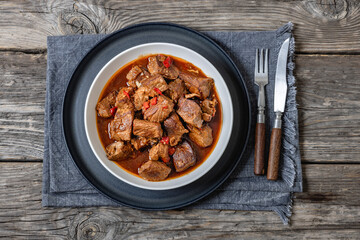beef stew in a white bowl on rustic wooden table